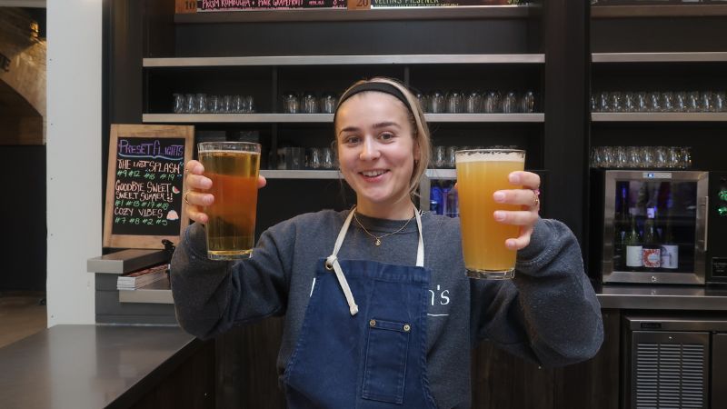 A woman holding up two beers